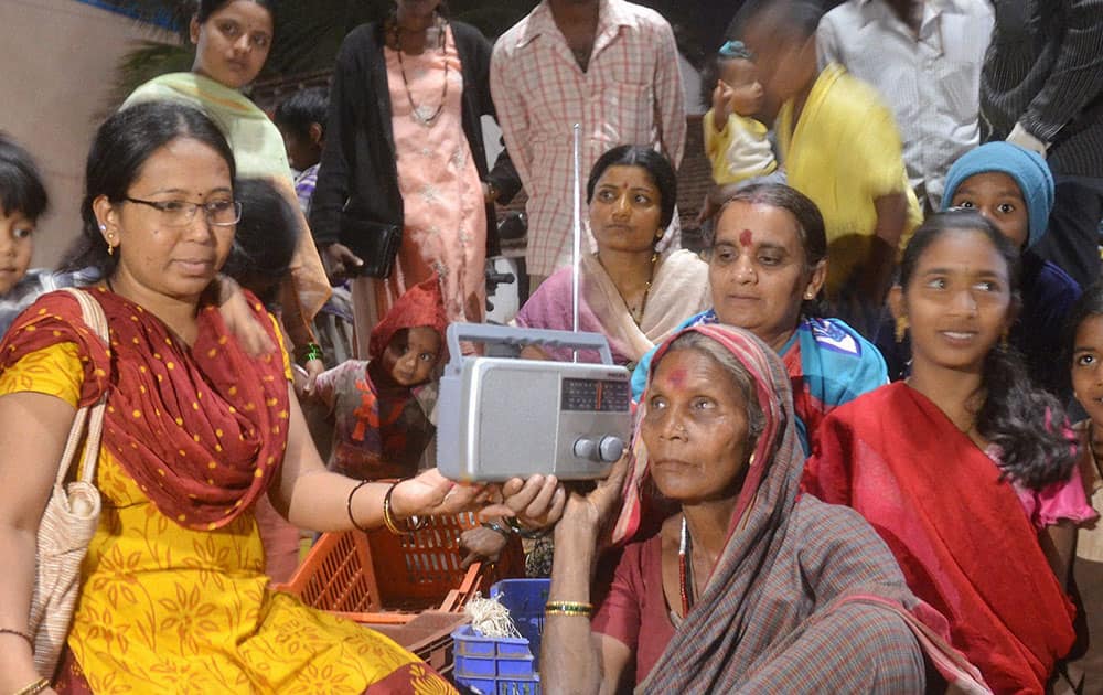 People listen to Prime Minister Narendra Modi and US President Barack Obama through the special episode of 'Mann ki Baat' at a village.