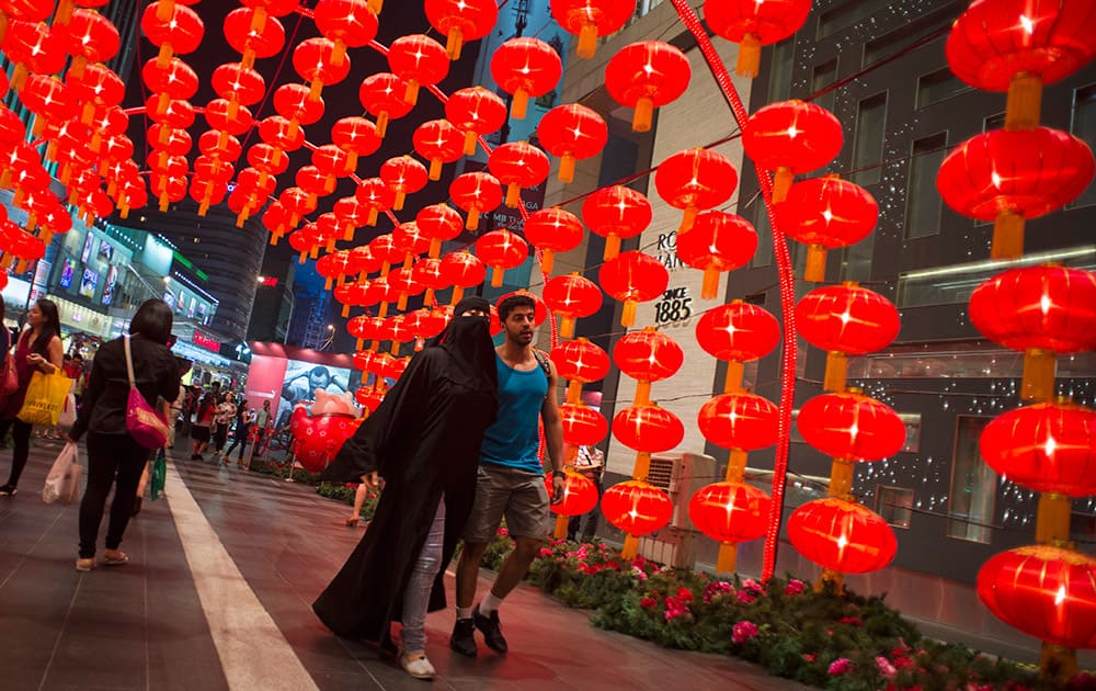 A Muslim tourist couple walks under an arch of traditional Chinese lanterns at a shopping mall in Kuala Lumpur, Malaysia.