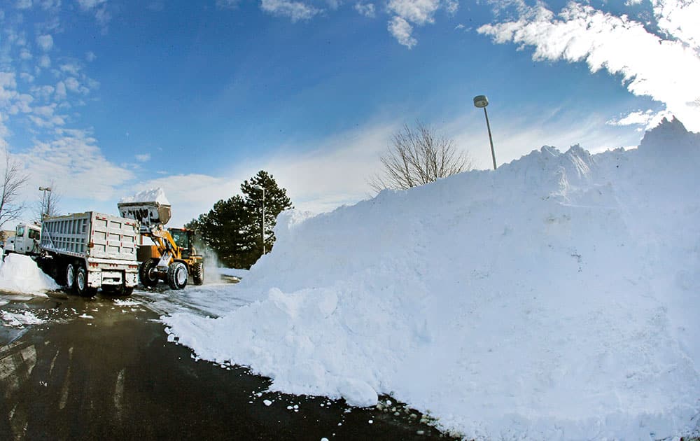 Workers remove snow from a mall parking lot, in Methuen, Mass., after a blizzard dumped over 2 feet of snow in some areas of the Merrimack Valley.