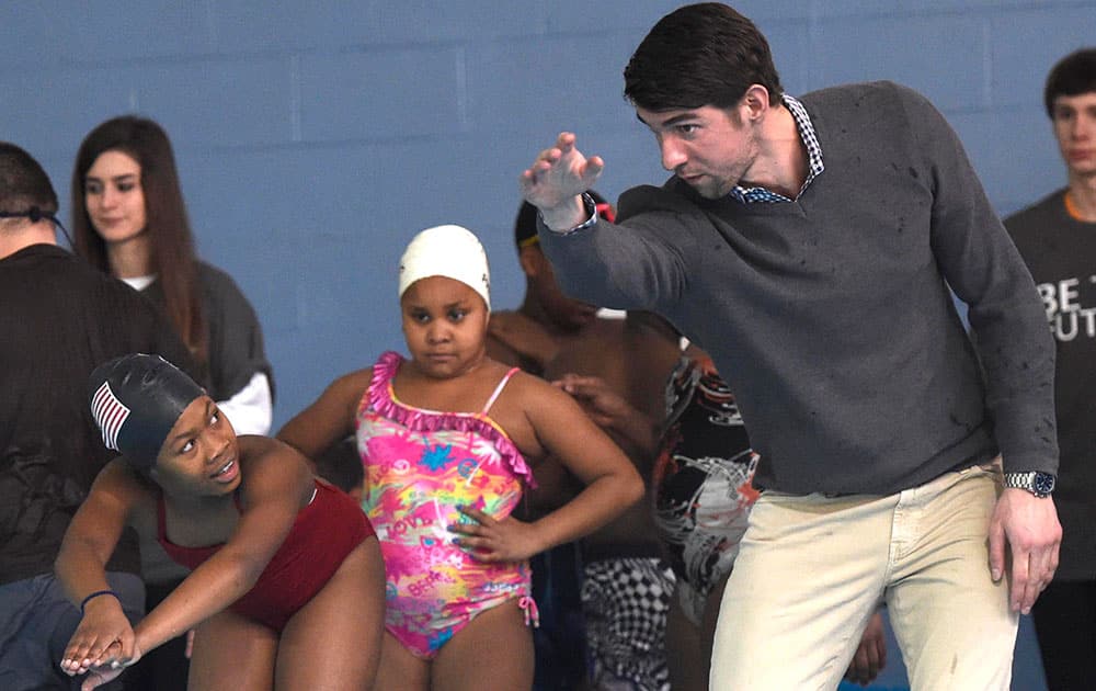 Olympic swimmer Michael Phelps, right, instructs Shakayla Blair, left, during swim team practice at the Haslam Family Club University, in Knoxville, Tenn. 