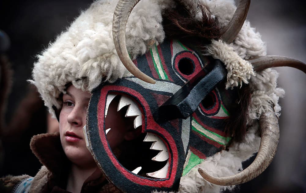 A young Bulgarian masked dancer pauses before a performance on the youth competition day during the 24th International Festival of Masquerade Games 