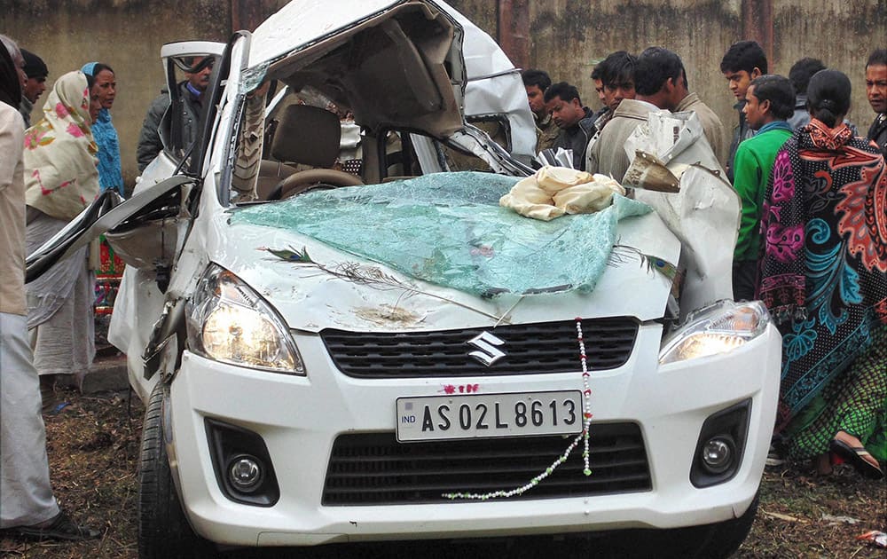 People looking at a damaged car that met with an accident at NH 15 at Jamugurihat in Sonitpur district of Assam.