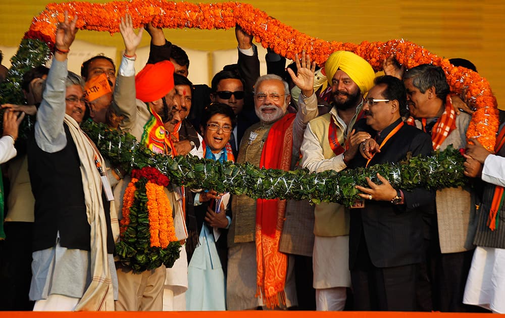 Prime Minister Narendra Modi, center right, waves to the crowd, with the Bharatiya Janata Party's chief ministerial candidate Kiran Bedi, center, standing beside him during an election campaign rally in New Delhi.