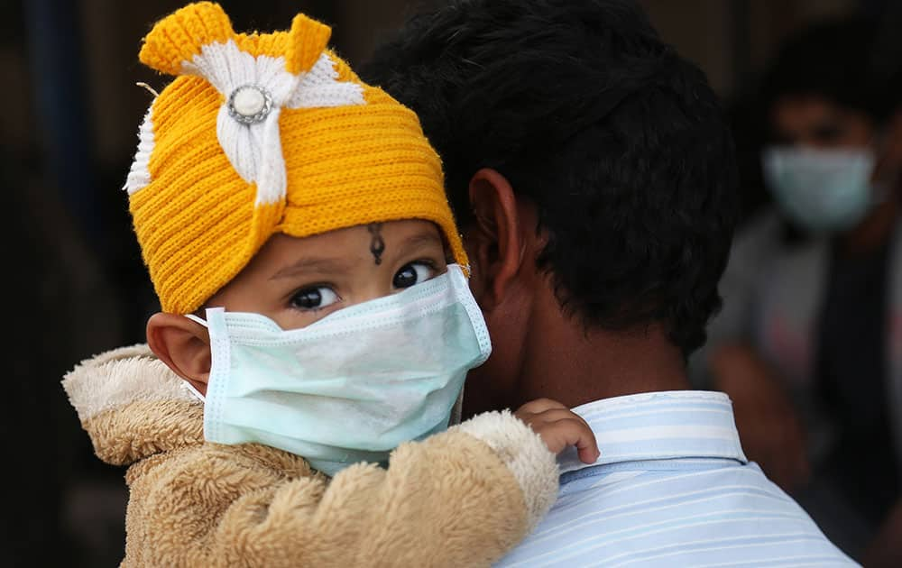 An Indian child, wearing a mask as preventive measures against swine flu, is carried by an adult inside Gandhi Hospital premise in Hyderabad.