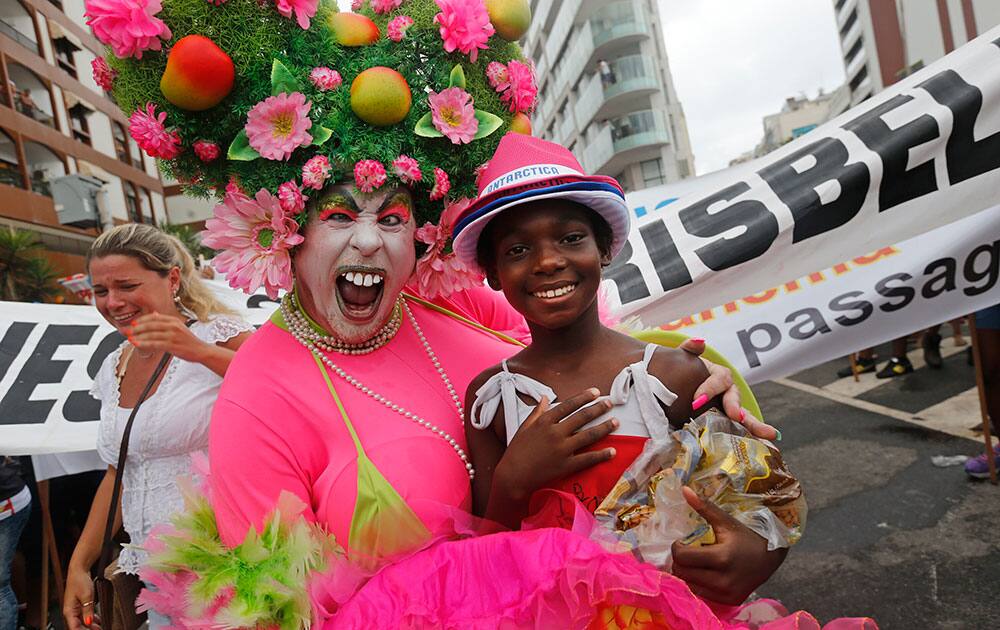 A reveler and a child street vendor pose for a photo during the Banda de Ipanema Carnival parade in Rio de Janeiro, Brazil.