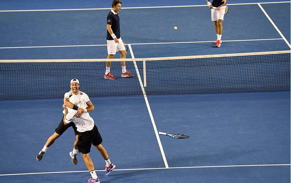 Italy’s Simone Bolelli, bottom right, embraces compatriot Fabio Fognini as they celebrate their men's doubles final win over France’s Pierre-Hugues Herbert, rear right, and Nicolas Mahut at the Australian Open tennis championship in Melbourne, Australia.