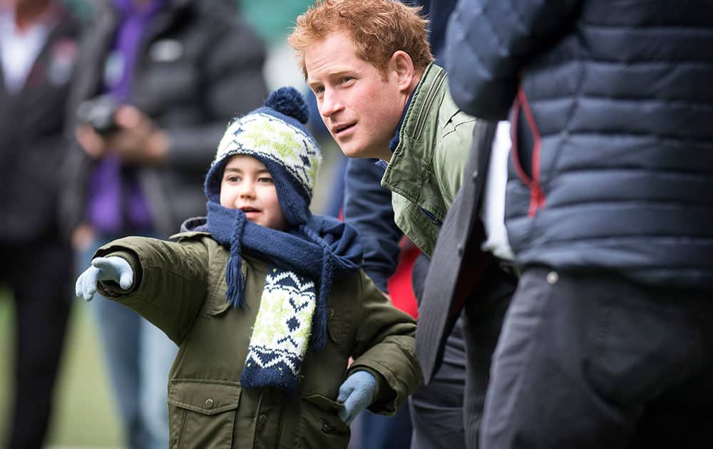 Britain's Prince Harry, right, patron of the RFU Injured Players Foundation (IPF), talks with Harrison Hogg, five, at Twickenham Stadium as they watch a training session for RFU/IPF runners who will taking part in this year's London Marathon.
