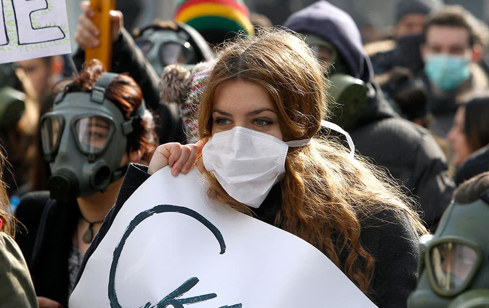 Environmentalists, wearing protective and gas masks, march through a street protesting against the polluted air in Skopje, Macedonia. A few hundred of environmentalists protested Sunday to raise awareness about air pollution and nature contamination.