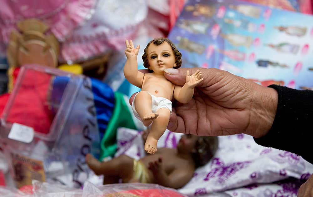 a woman holds a small statue of baby Jesus as she decides what costume to buy for it at La Merced market in preparation for the feast day of the Virgin of Candelaria in Mexico City. Each year on Feb. 2, Mexico's Catholic faithful honor the story of the infant Christ being presented before the temple in Jerusalem by adorning a figure of baby Jesus in fine clothing and praying for blessings throughout the year. 