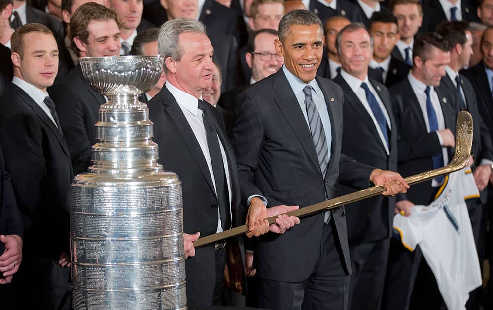 LA Kings head coach Darryl Sutter hands President Barack Obama, center, a hockey stick during a ceremony to honor both the 2014 NHL Champion Los Angeles Kings and 2014 MLS Cup Champion LA Galaxy in the East Room of the White House.