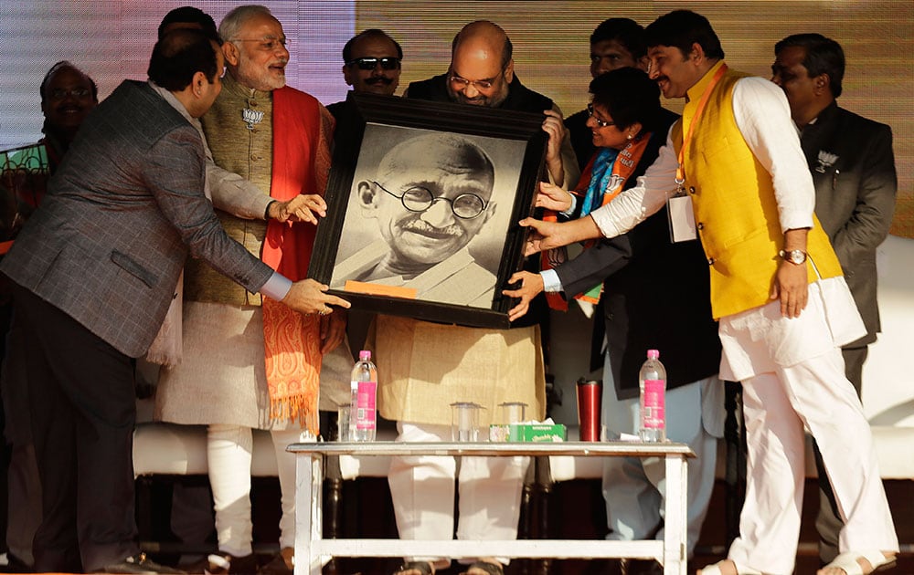 Indian Prime Minister Narendra Modi, second left, Bharatiya Janata Party President Amit Shah, center, and the party's chief ministerial candidate Kiran Bedi, second right, hold a portrait of Mahatma Gandhi presented to them during an election campaign rally in New Delhi.