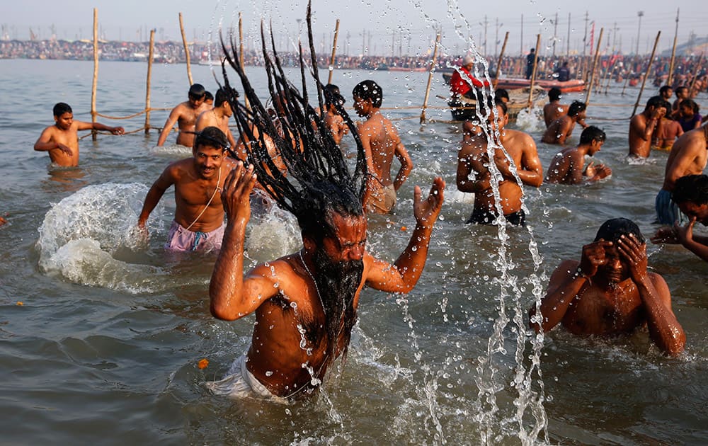 An Indian holy man with other Hindu devotees take holy dips at Sangam, the confluence of the Rivers Ganges, Yamuna and mythical Saraswati on Maghi Purnima, or the full-moon day of the month of Magh during the annual traditional fair of “Magh Mela” in Allahabad.
