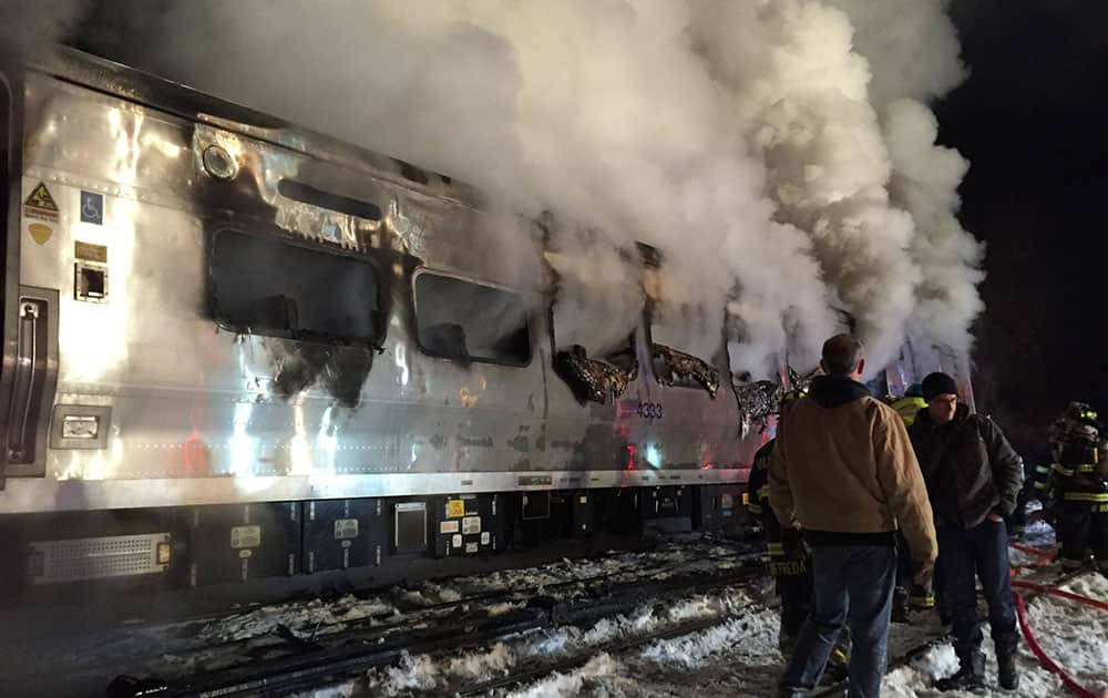 A Metro-North Railroad passenger train smolders after hitting a vehicle in Valhalla, N.Y.,