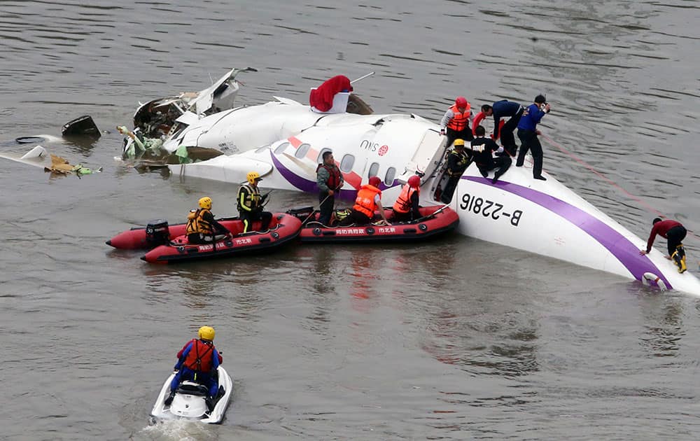 Emergency personnel approach a commercial plane after it crashed in Taipei, Taiwan. The Taiwanese commercial flight with 58 people aboard clipped a bridge shortly after takeoff and crashed into a river in the island's capital of Taipei on Wednesday morning. 