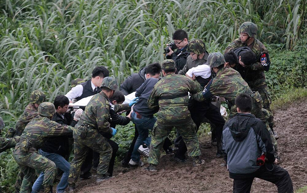 Soldiers and rescue personnel carry the body of a passenger from a commercial plane after it crashed in Taipei, Taiwan.