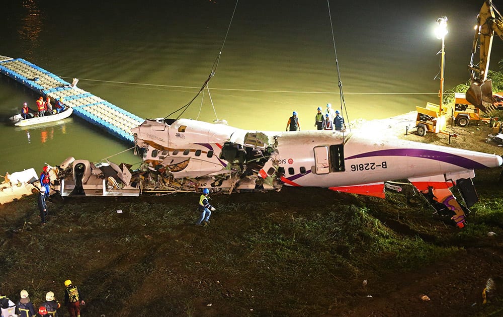 The mangled fuselage of a TransAsia Airways commercial plane is dragged to the river bank after it crashed in Taipei, Taiwan.