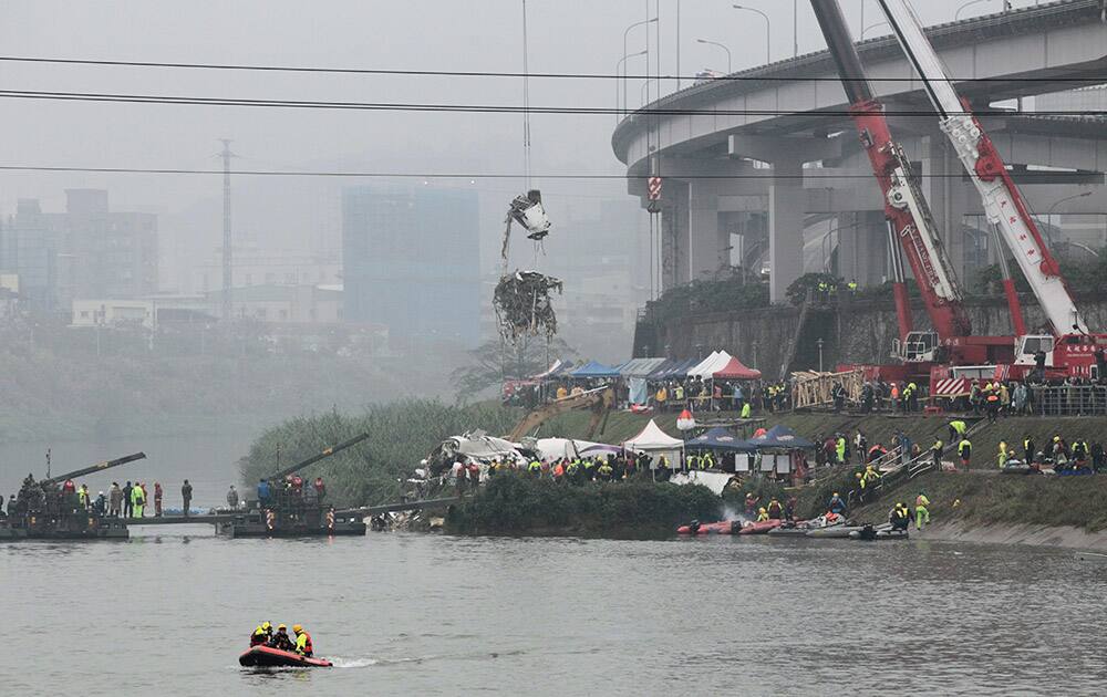 A crane lifts parts of wreckage at the site of a commercial plane crash in Taipei, Taiwan.