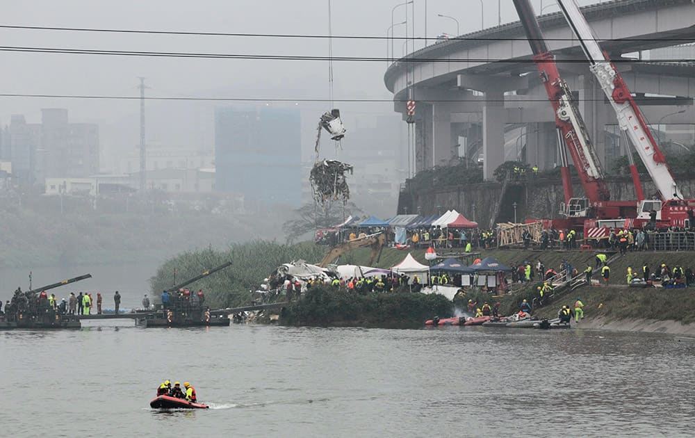 A crane lifts parts of wreckage at the site of a commercial plane crash in Taipei, Taiwan.