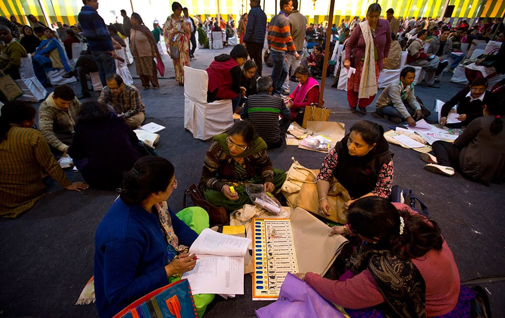 Electoral workers tally poll materials handed out to them at a distribution center on the eve of Delhi elections in New Delhi. 