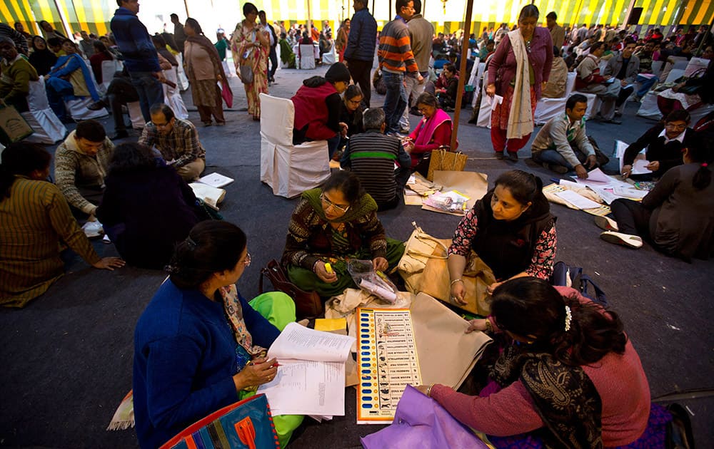 Electoral workers tally poll materials handed out to them at a distribution center on the eve of Delhi elections in New Delhi.