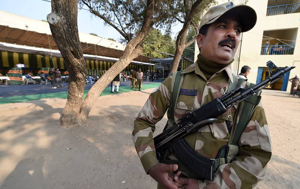 A security person guards a training camp for the poll officials , on the eve of Assembly elections in New Delhi.