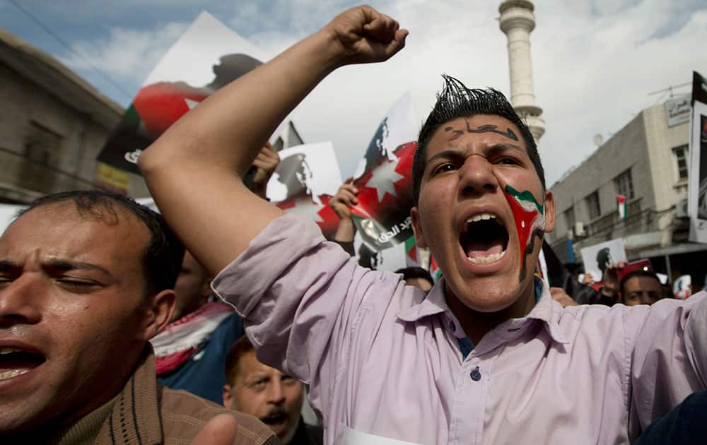 Demonstrators, one with a Jordanian flag image painted on his face and Arabic that reads, 