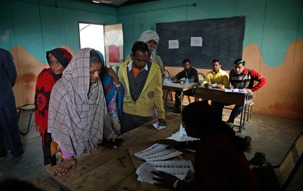 A polling officer verifies the name of a voter before allowing her to proceed to cast her vote at a polling station in New Delhi.
