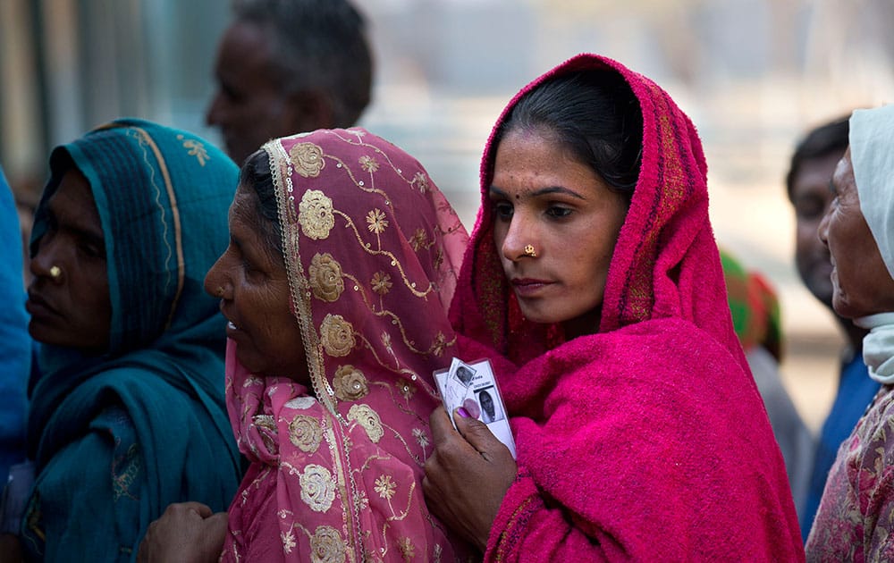 women wait in a queue to cast their votes at a polling booth in New Delhi,