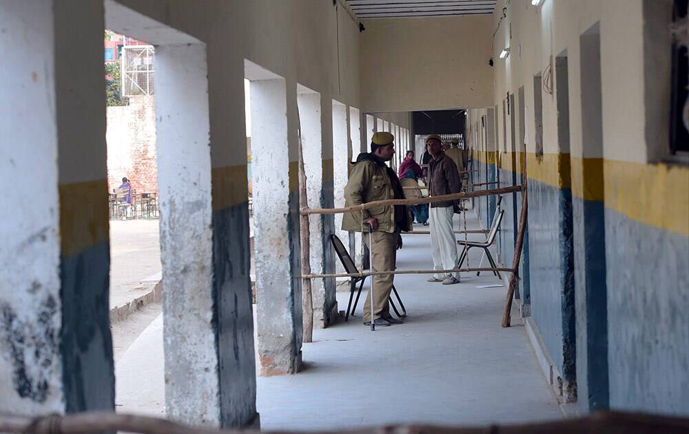 Security personnels keep vigil outside a polling booth during the Assembly elections at Trilokpuri in New Delhi.