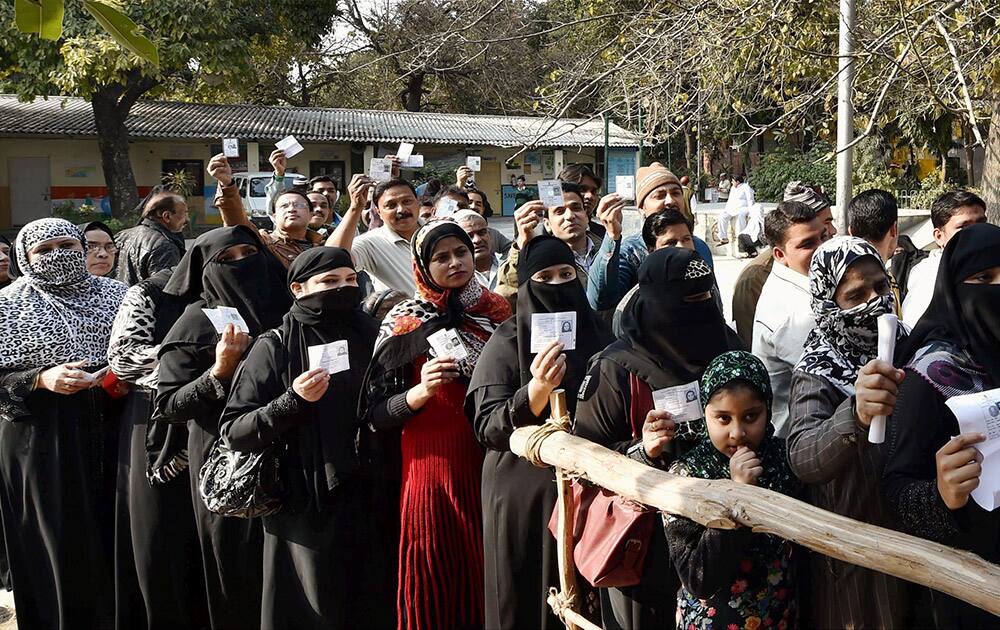 Voters wait to cast their votes for the Delhi Assembly elections at a polling station at walled city, in New Delhi.