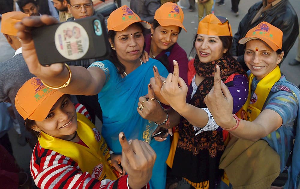 Voters take Selfie outside a polling station during the assembly elections in East Delhi.