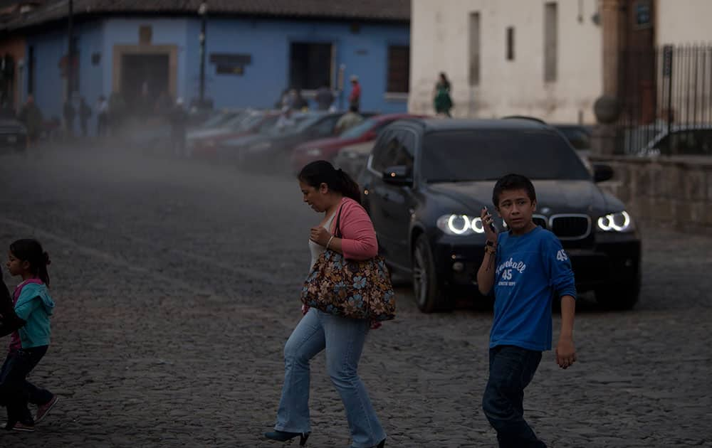 People cross a street covered with ash from the eruption of the Fuego Volcano at Antigua Guatemala.