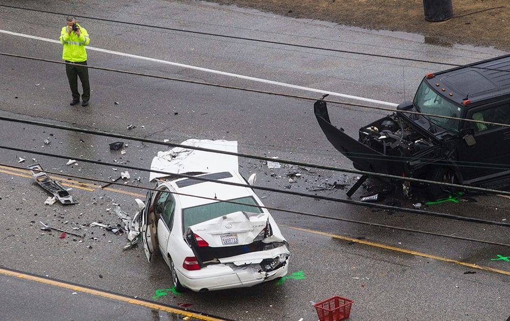 A Los Angeles County Sheriff's deputy photographs the scene of a car crash where one person was killed and at least seven other's were injured.