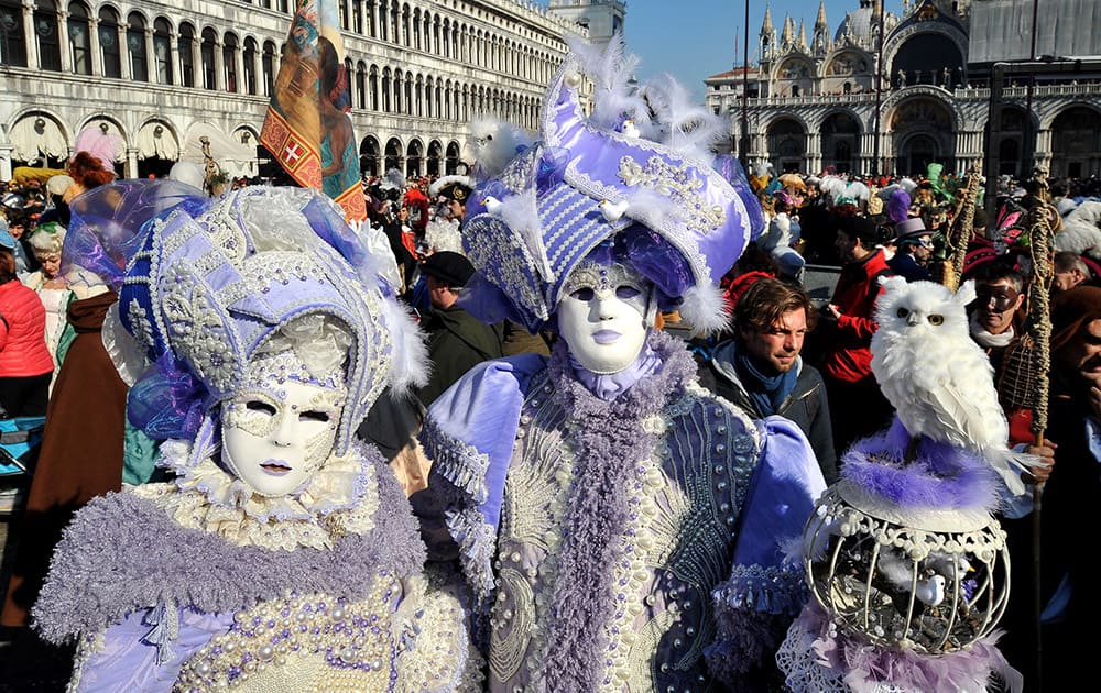 People wearing traditional costumes parade in St. Mark's square in Venice, Italy, Sunday on the occasion of the Venice Carnival.