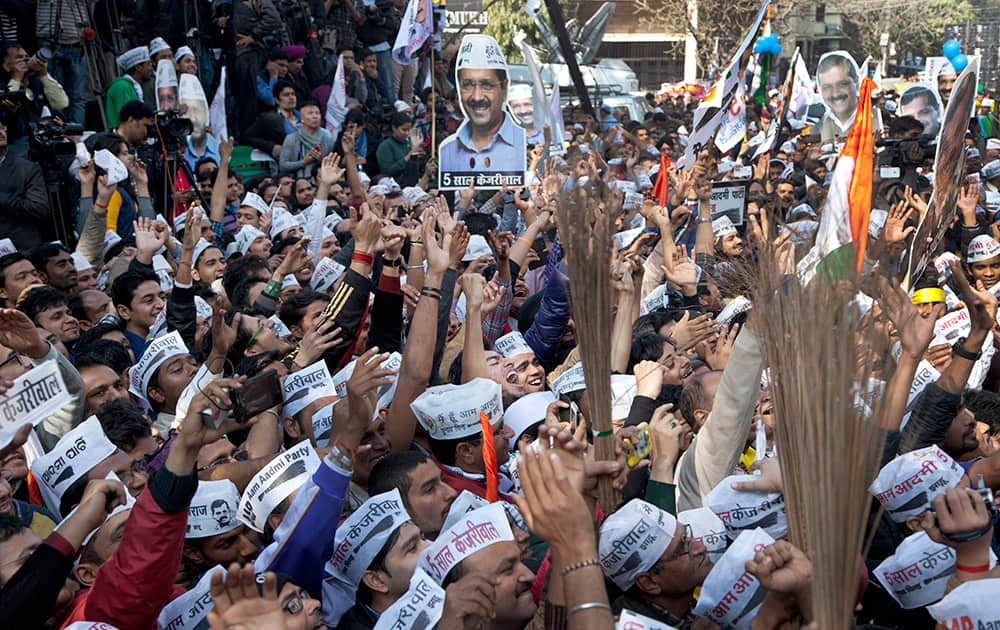 Supporters of the Aam Aadmi Party, holds cut-outs of their leader Arvind Kejriwal and their party symbol, the broom, as they celebrate the party's victory in New Delhi.