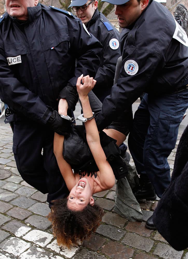 A Femen activist is led away by police officers as she protests in front of Lille courthouse in Lille, northern France, where Dominique Strauss-Kahn goes on trial for sex charges in France.