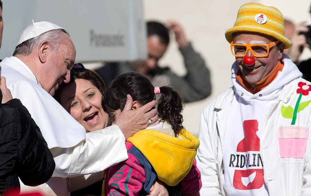 Pope Francis caresses a young girl during his weekly general audience in St. Peter's Square, at the Vatican.