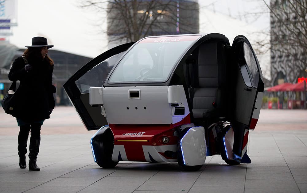 A woman poses for photographers beside a prototype driverless car called a LUTZ (Low-carbon Urban Transport Zone) Pathfinder Pod during a launch event for the media near the O2 Arena in London.