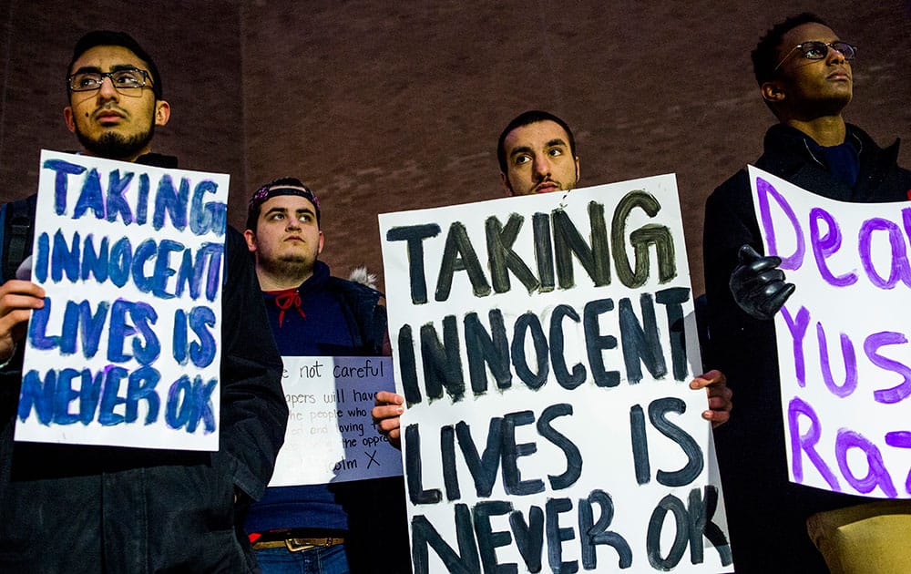 University of Michigan-Flint students, from left to right, Bilal Ali, Michael Puro, Mohamed Samman and Zafir Abutalih attend a vigil at the school in downtown Flint, Mich., in memory of three people who were killed Tuesday near UNC-Chapel Hill, N.C. Craig Stephen Hicks appeared in court Wednesday on charges of first-degree murder in the deaths of Deah Shaddy Barakat, his wife Yusor Mohammad and her sister Razan Mohammad Abu-Salha.