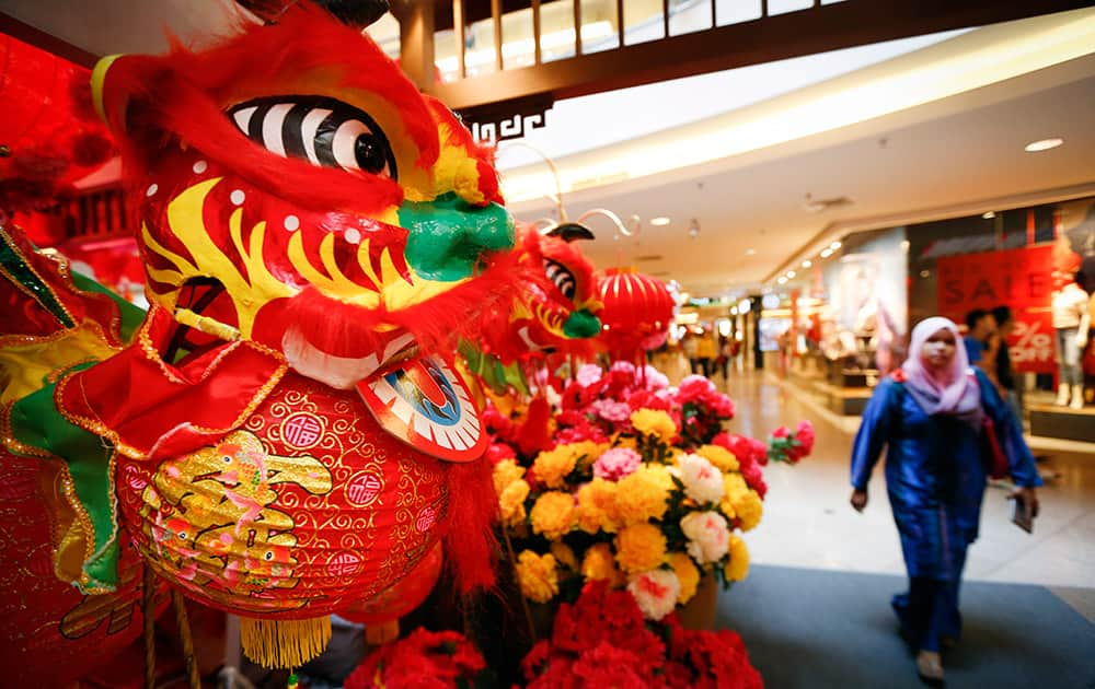 A Malay shopper walks near Lunar New Year decorations on display at a shopping mall in Kuala Lumpur, Malaysia.