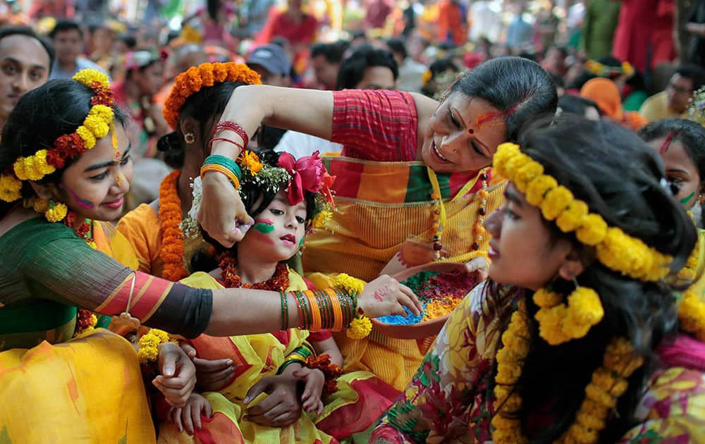 Bangladeshi girls put vermillion powder on each other as they celebrate the arrival of spring on the first day of Falgoon at the Dhaka University campus in Dhaka, Bangladesh.