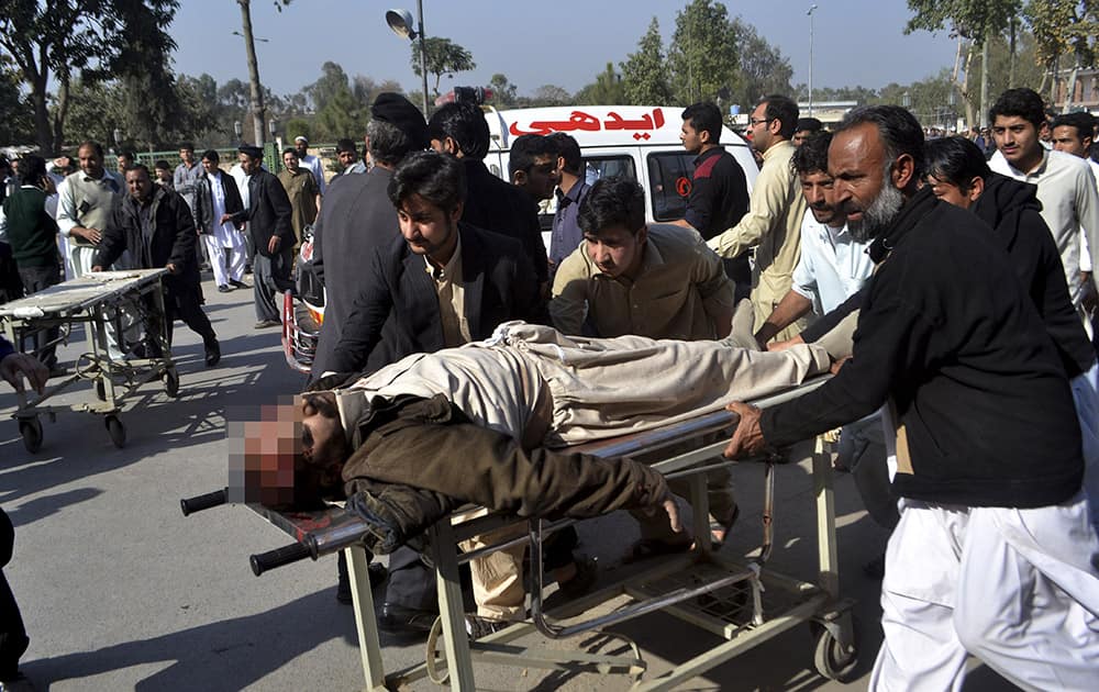 People rush an injured person to a hospital following an attack involving suicide bombers and gunmen at a Shiite mosque in Peshawar, Pakistan.