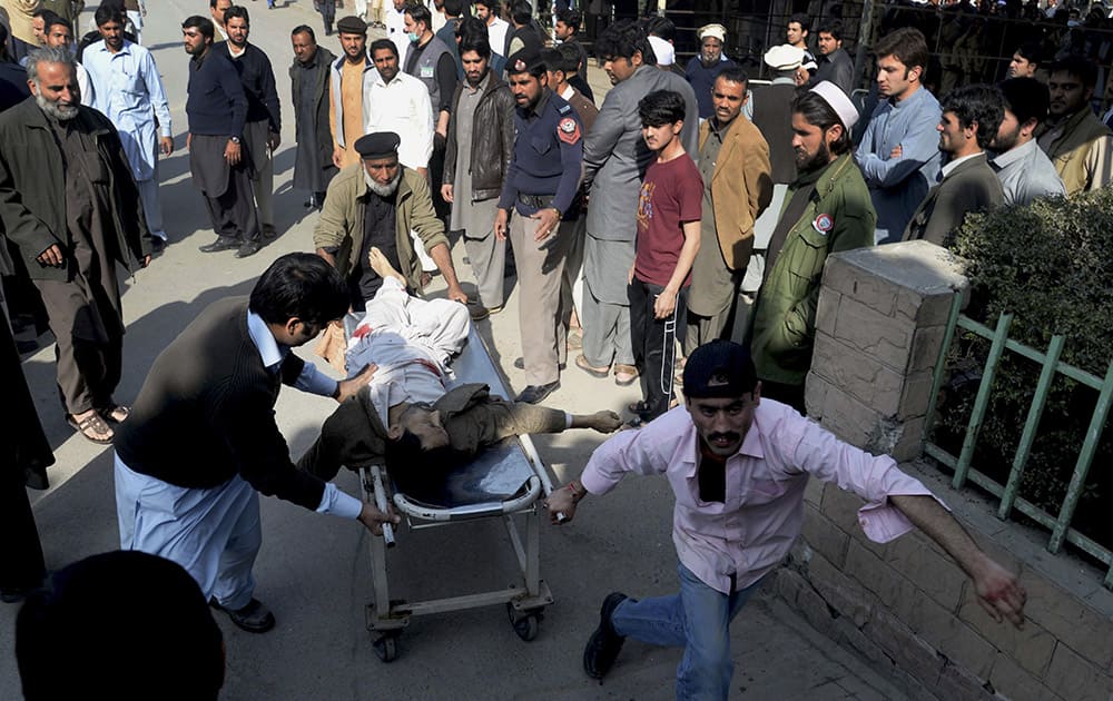 People rush an injured person to a hospital following an attack involving suicide bombers and gunmen at a Shiite mosque in Peshawar, Pakistan.