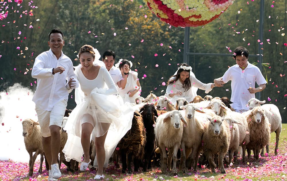 Three newlywed couples run away from a giant flower ball as a part of an adventure-themed wedding ceremony in Ratchaburi Province, Thailand.