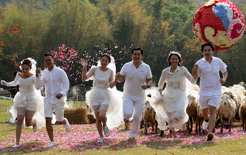 Brides and grooms run away from a giant flower ball as a part of an adventure-themed wedding ceremony in Ratchaburi Province, Thailand, on the eve of Valentine's Day. 