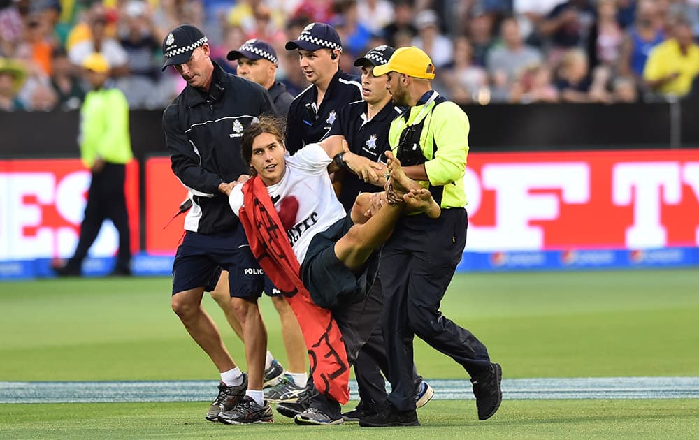 A pitch invader is carried off the field by security during their Cricket World Cup pool A match between Australia and England in Melbourne, Australia.