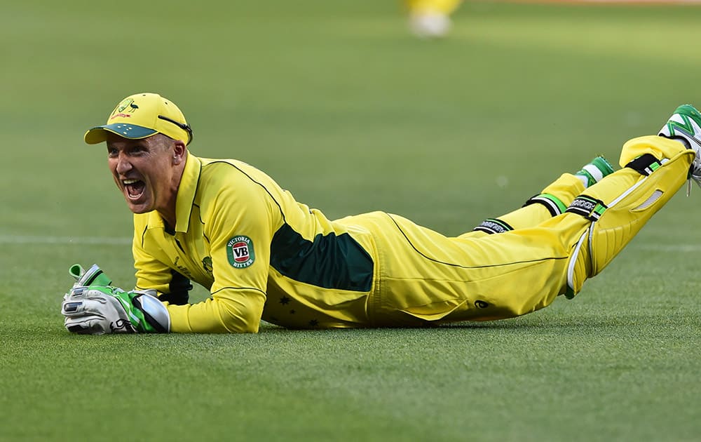 Australia's wicketkeeper Brad Haddin slides along the ground after catching out England's Jos Buttler during their Cricket World Cup pool A match in Melbourne, Australia.