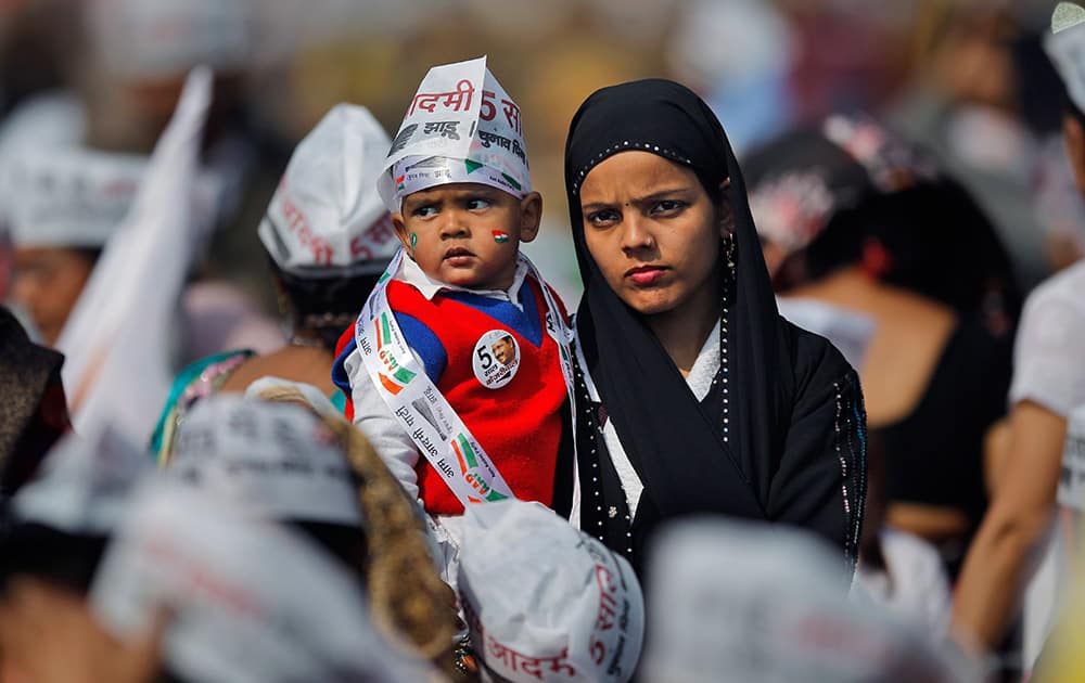 A woman carries a child and attends the oath-taking ceremony of Aam Aadmi Party, leader Arvind Kejriwal as chief minister of Delhi in New Delhi.