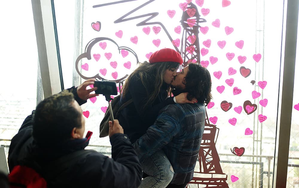 A couple kiss on the first floor of the Eiffel Tower, during Valentine's day, in Paris.