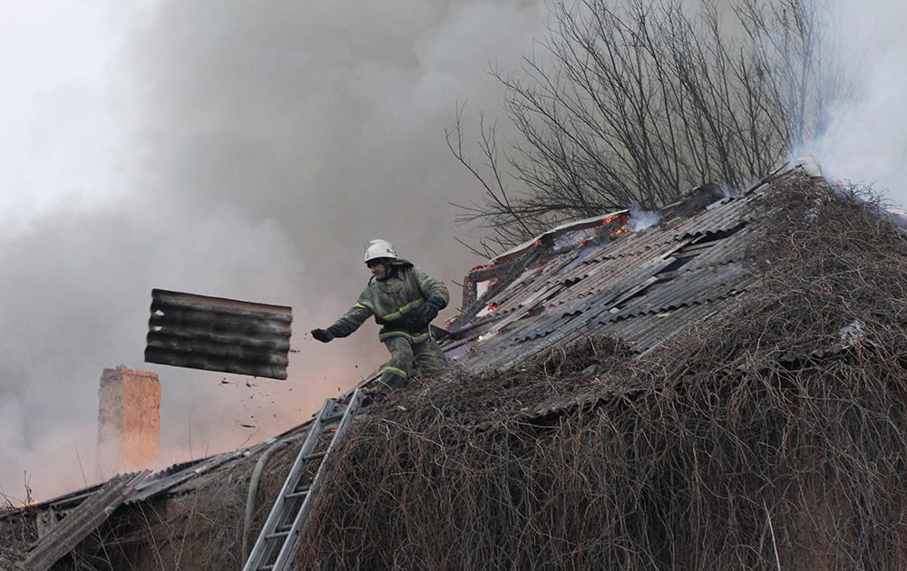 A firefighter dismantles a roof to extinguish a building on fire after shelling between Russian-backed separatists and Ukrainian government in residential area of the town of Artemivsk.